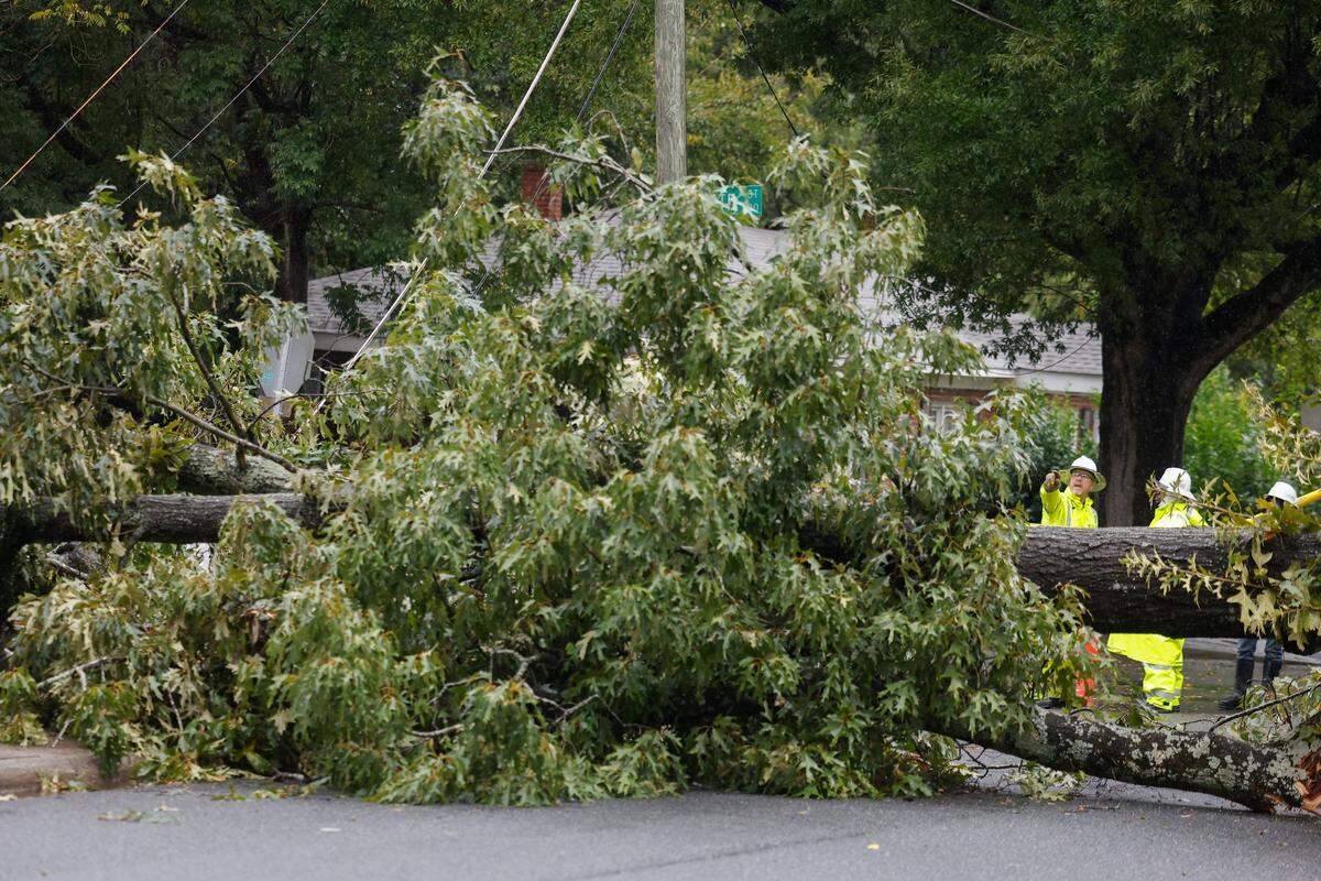 Duke Energy employees examine a fallen tree lays across Holt Street as Hurricane Ian and its remnants begins to arrive in Charlotte, N.C., Friday., Sept. 30, 2022.