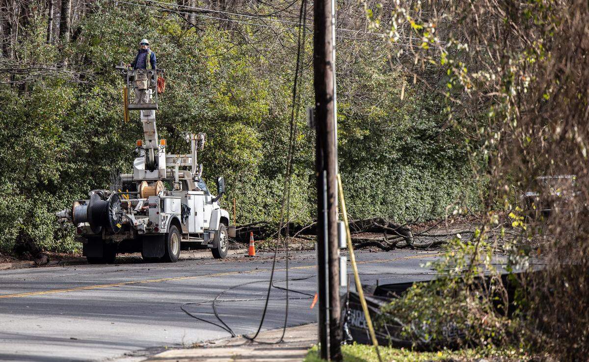 A crew works on repairing downed power lines on Randolph Road in Charlotte, NC, on Monday, January 3, 2022. A winter storm crossed the Carolinas overnight, knocking down trees and branches onto power lines and cutting electricity to thousands across the region.