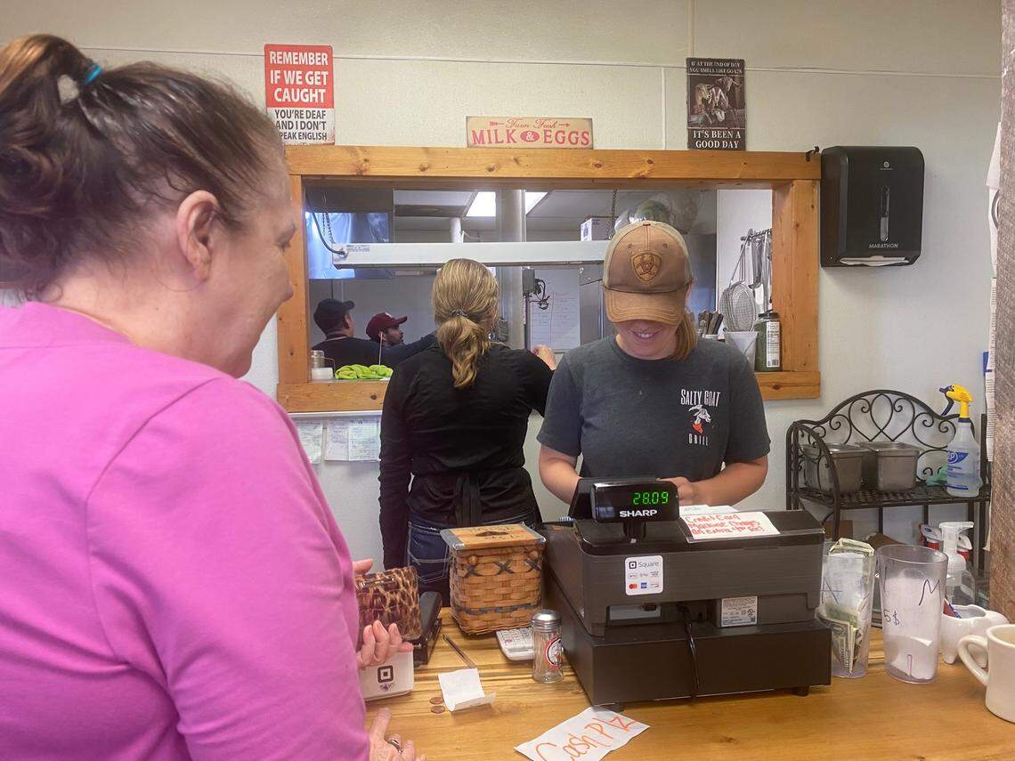 Salty Goat Grill co-owner Erin Vazquez rings up a customer’s bill.