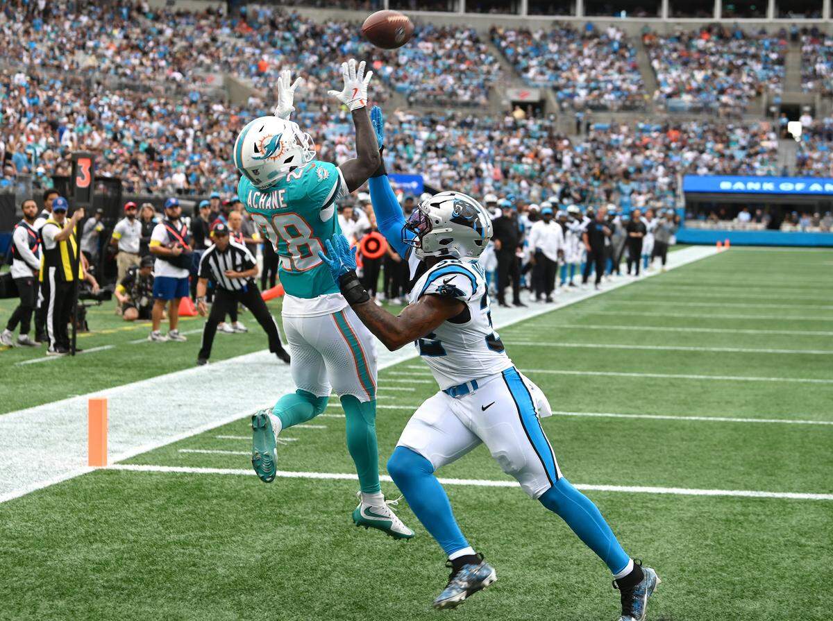 Miami Dolphins running back De'Von Achane, left, leaps to catch a pass in the end zone as Carolina Panthers linebacker Trevin Wallace, right, applies pressure during action on Sunday, October 5, 2025 at Bank of America Stadium in Charlotte, NC.