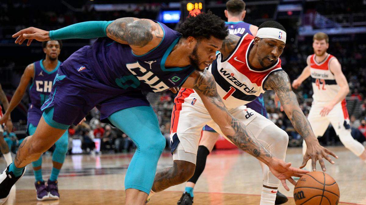 Washington Wizards guard Kentavious Caldwell-Pope (1) and Charlotte Hornets forward Miles Bridges (0) battle for the ball during the first half of an NBA basketball game, Monday, Jan. 3, 2022, in Washington. (AP Photo/Nick Wass)