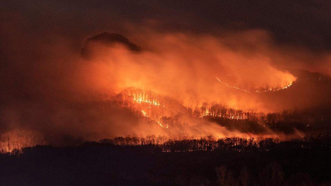 Smoke envelopes the landmark pinnacle (top left) as a wildfire burns on the north side of the mountain at Pilot Mountain State Park on Sunday, Nov. 28, 2021.