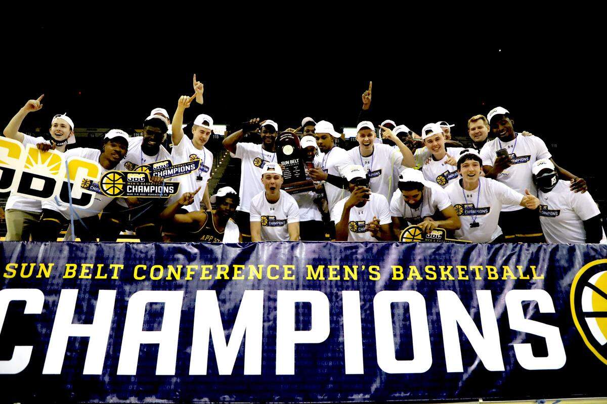 Members of the Appalachian State men’s basketball team pose on March 8, 2021, after winning the Sun Belt conference championship and securing the team’s first NCAA tournament berth since 2000.