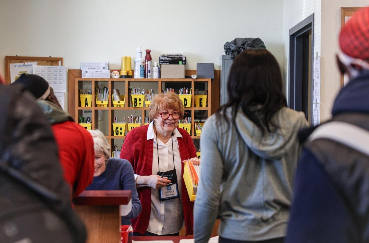 Volunteer Susan Lohr, center, speaks with people seeking mail at Roof Above. Mail pick-up is just one service the nonprofit offers to help people experiencing homelessness.