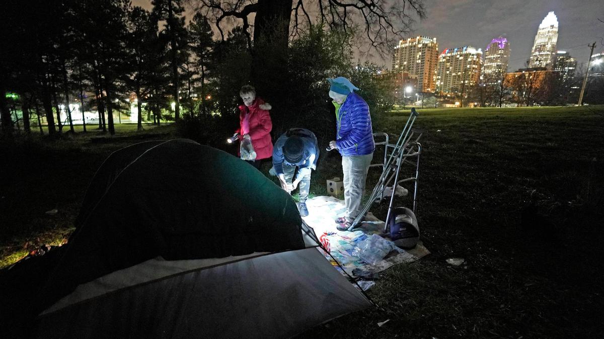 Homeless advocate Juaniska Davis, center, and Sharon McCarthy, right, interview a homeless man in his tent near uptown Charlotte as Mecklenburg County Commissioner Pat Cotham, left, listens in during the annual ‘point in time’ canvas of the homeless on Thursday, January 30, 2020.