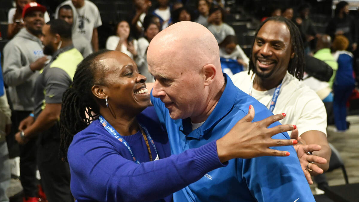 North Meck head basketball coach Duane Lewis, right, is hugged by a fan as the crowd celebrates the team’s 57-47 win in the NCHSAA 4A State Championship at Lawrence Joel Veterans Memorial Coliseum in Winston-Salem, NC. North Meck defeated Hanover for the victory.