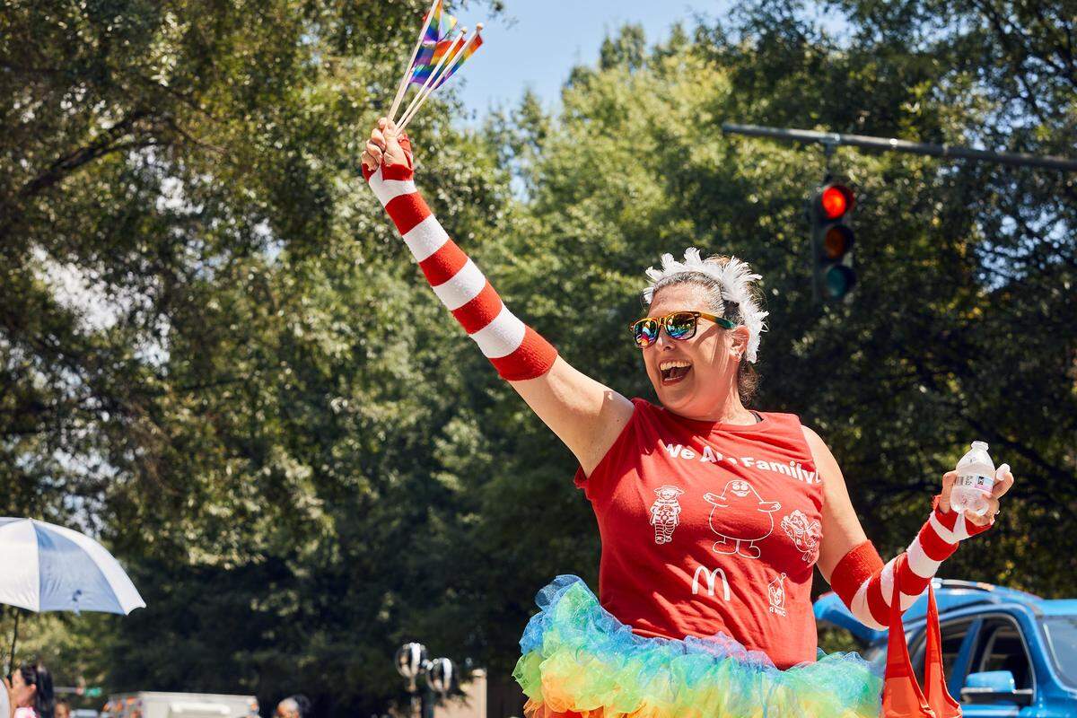 McDonald’s parade staff waves flags towards the crowd as the parade passes 7th Street during the 25th Charlotte Pride Parade in uptown Charlotte on August 17, 2025.