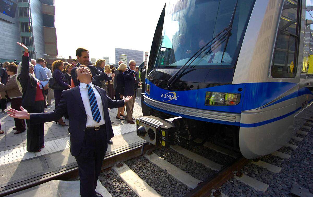 Charlotte Mayor Pat McCrory (left) smiles skyward in front of a Lynx light rail train with Ron Tober, chief executive of the Charlotte Area Transit System, at the controls during a dedication ceremony in 2007.