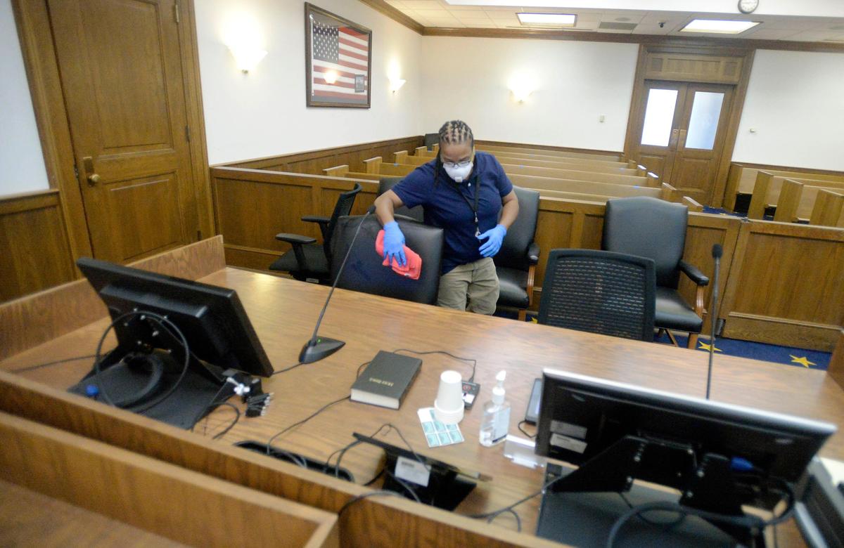 Georgette Charles, cleaning supervisor at the federal courthouse in Charlotte, wipes down a chair at the defendant table after spraying disinfectant inside one of the courtrooms on Friday, April 10, 2020. Charles disinfects the courtrooms before, between, and after sessions during the day. The Western District of North Carolina, with main courthouses in Charlotte and Asheville, is the only federal judicial circuit in the country cleaning before and after all court activity.