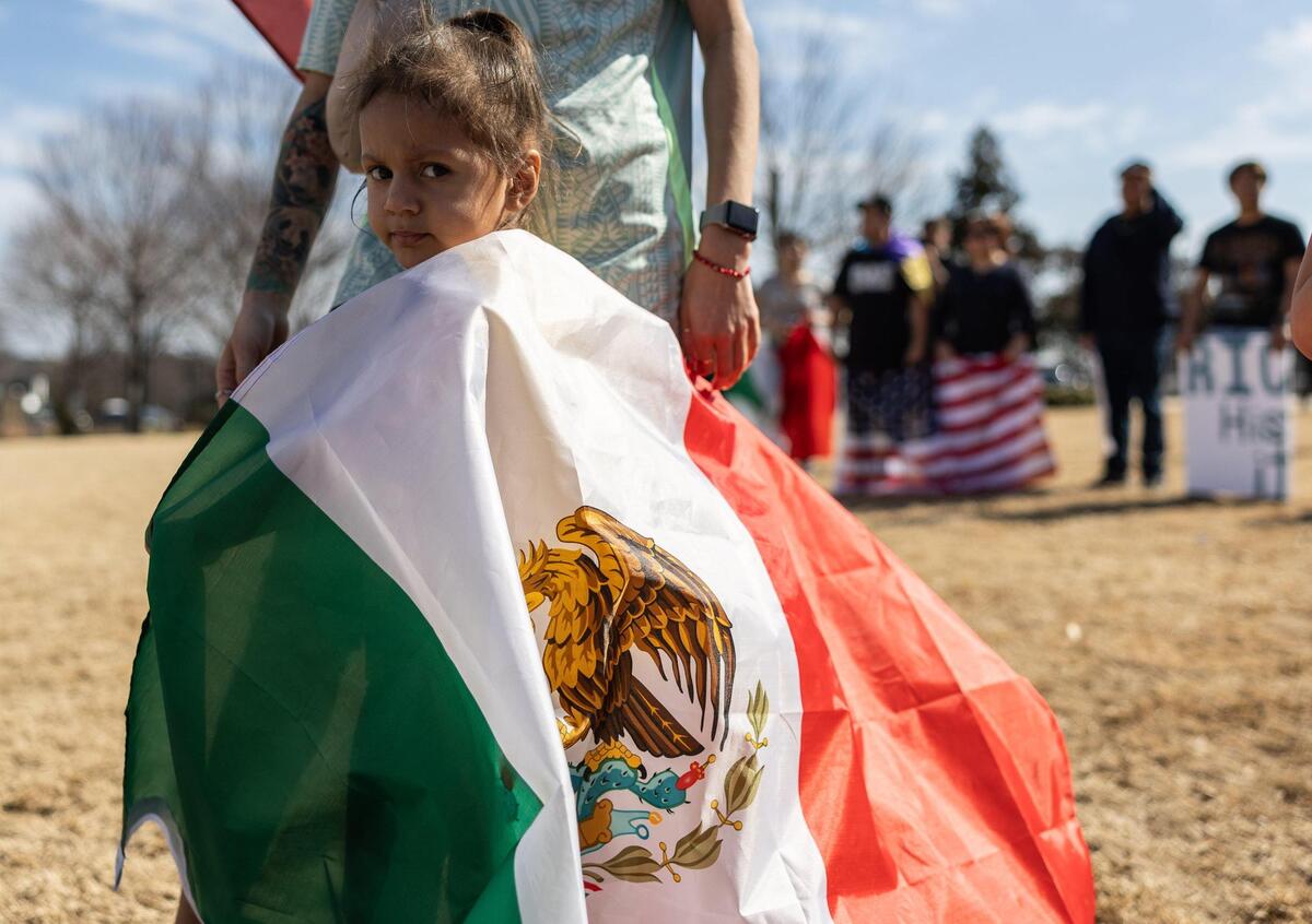 Claudia Toloza, 3, clings to her mom, Noelle, during the “Stop the Deportations” protest on Sunday at First Ward Park in Charlotte.