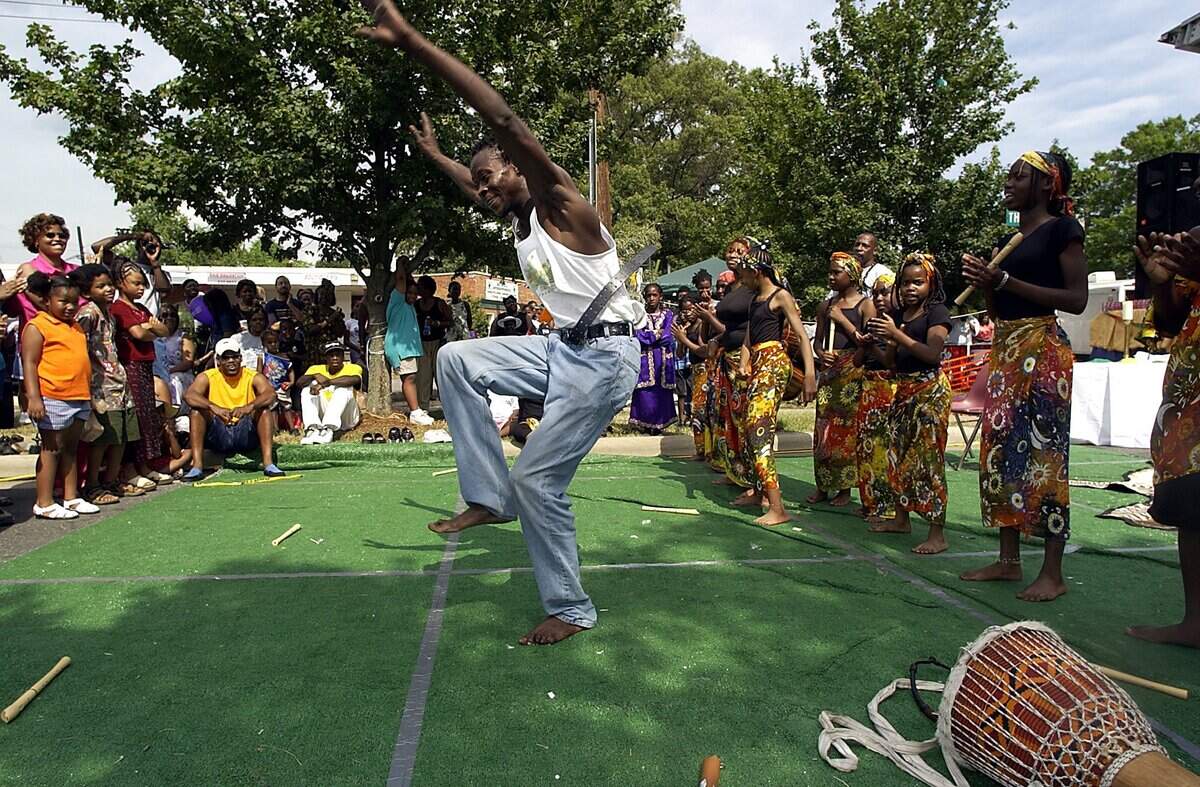 Baba Michael Memby, center, dances with members of the Sugar Creek Charter School (right) on Sunday afternoon, June 16, 2002 during the 5th Annual Juneteenth Festival of the Carolinas on Thomas Avenue in Charlotte.