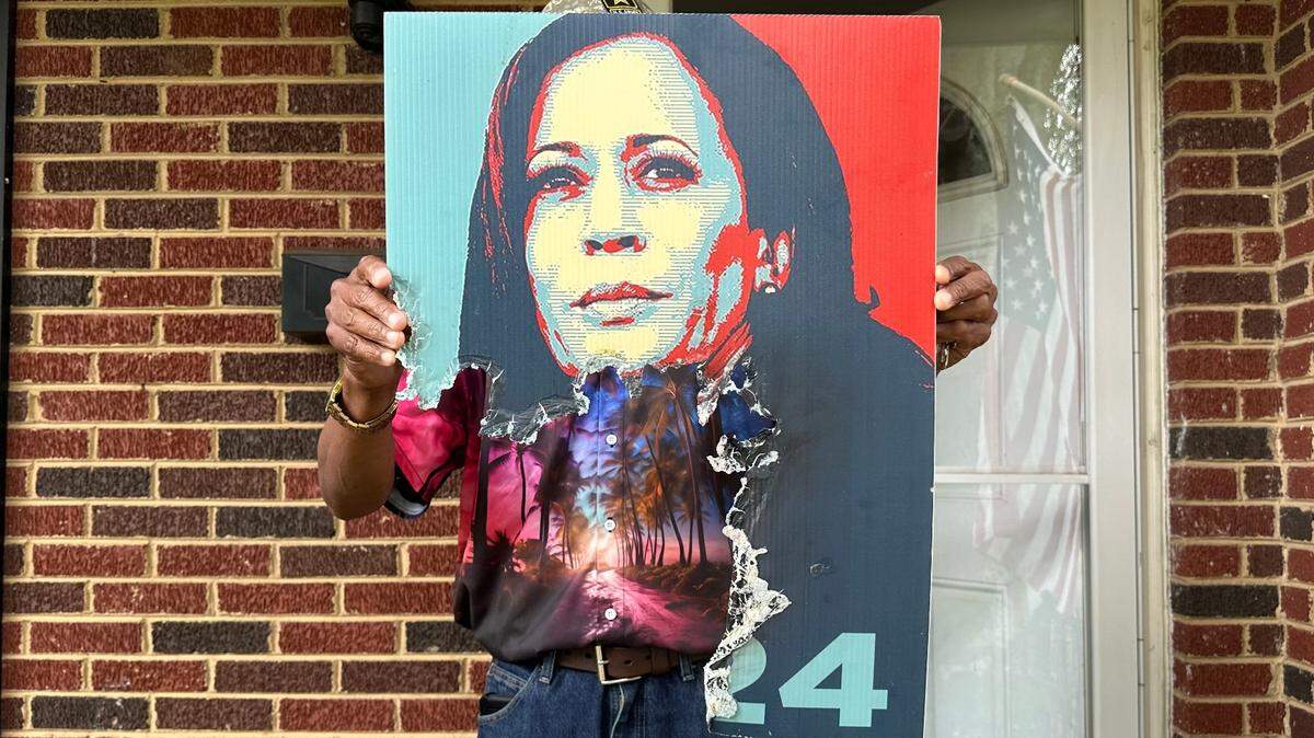 Ray Kodzai holds up his burned Kamala Harris sign outside his home in south Charlotte on Friday, Sept. 13, 2024.