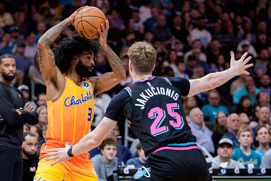 Coby White of the Charlotte Hornets looks to pass while guarded by Kasparas Jakucionis of the Miami Heat during their game at Spectrum Center on March 06, 2026.