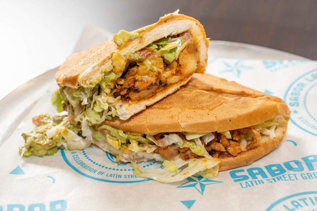 The Mexican Torta at Sabor has al-pastor pork, refried beans, mozzarella cheese, lettuce, sour cream and freshly made guacamole on a toasted bolillo bun.