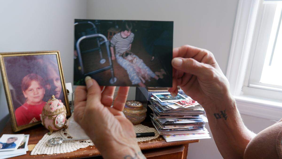 A mother displaying a poster in her home's living area.