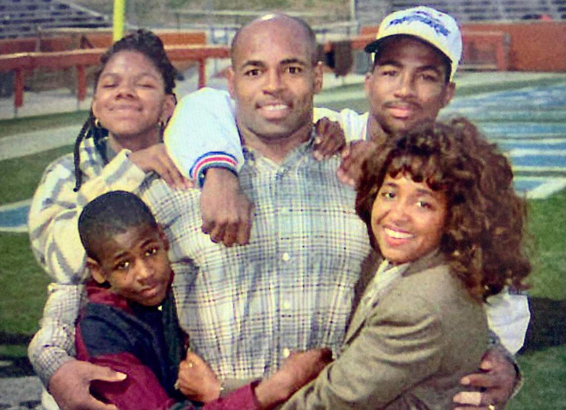 In 1995, Carolina Panthers linebacker Sam Mills posed for The Charlotte Observer while surrounded by his family, including wife Melanie and three of their four children. Sam Mills III is at the top right, in the Panthers cap. The photo was taken at Clemson, S.C., where the Panthers played their home games during their inaugural season.