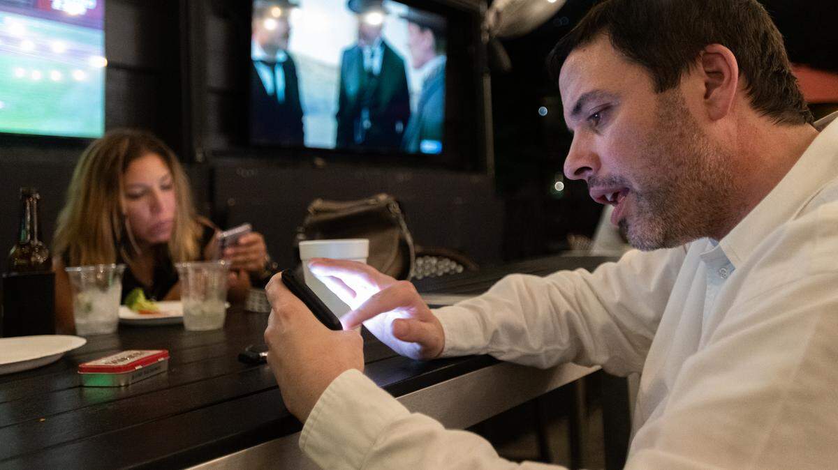 Guests at Selwyn Avenue Pub check their phones for the latest election results in Charlotte, N.C. on Tuesday evening, July 26, 2022.