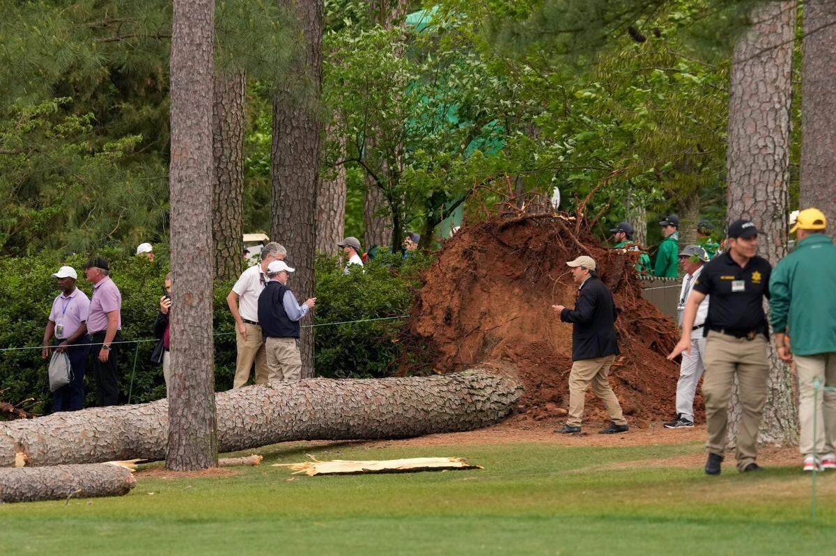 Volunteers and staff secure the area around where a tree fell near the 17th tee during the second round of The Masters golf tournament.