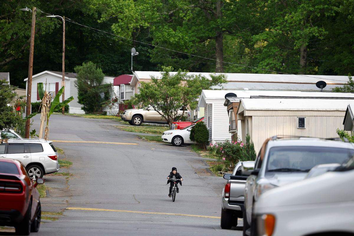 A boy rides his bike near mobile homes at Bellhaven Estates mobile home park in Charlotte, on May 2, 2022.