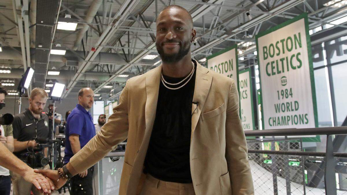 Former Charlotte Hornets guard Kemba Walker shakes a hand as he leaves an interview at the Celtics’ basketball practice facility Wednesday in Boston.