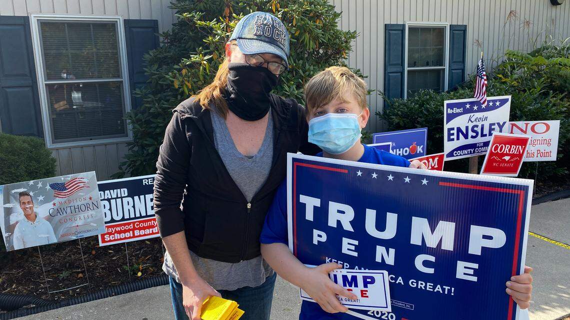 Kelsi Williams, 35, hands out signs and voter guides with her son, Mason Hunter, for the Haywood County Republican Party in Waynesville, N.C. on a recent Friday.