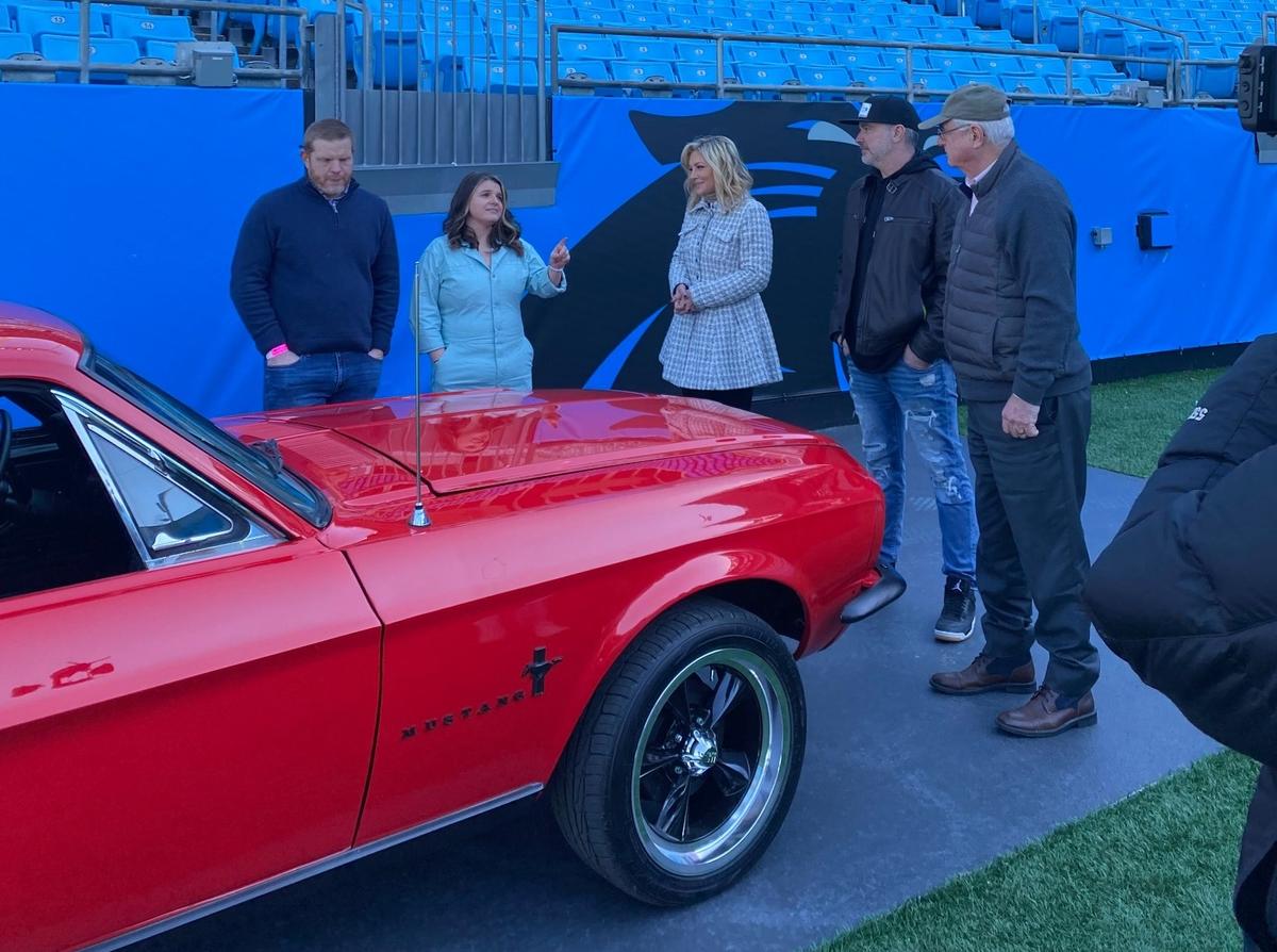 Danielle Trotta, center, meets with a “My Dream Car!” family (from left, Dave Kiehn, Amie Kiehn, Rick Pearson and Douglas Kiehn) at Bank of America Stadium in Charlotte.