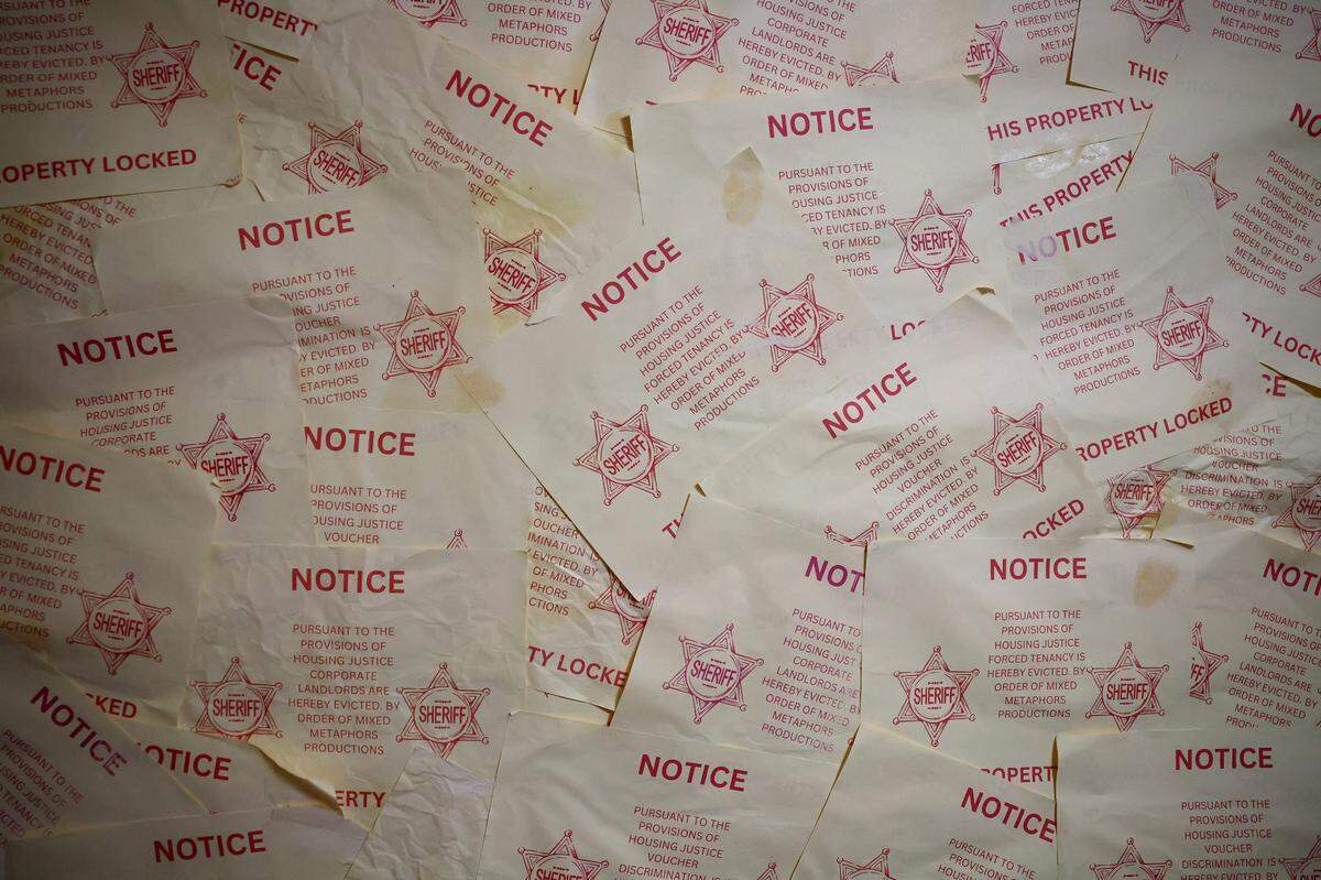 Notices of eviction cover a wall in the QC Family Tree’s Big Blue House in Charlotte, NC as actors prepare for an immersive play on gentrification on Tuesday, August 13, 2024.