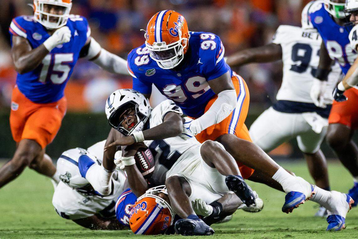 Florida defensive lineman Cam Jackson (99) and edge George Gumbs Jr. (34) tackle Samford quarterback Quincy Crittendon (2) during a 2024 game.