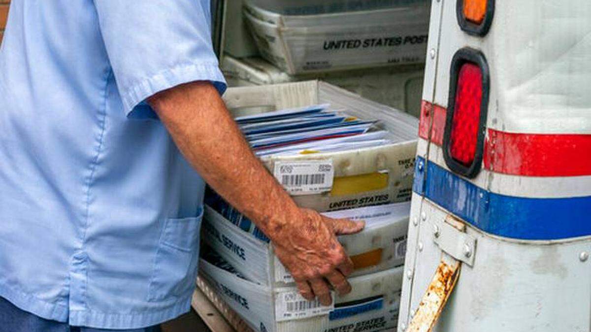 A U.S. Postal Service carrier loads mail onto a truck July 31 at a McLean, Virginia mail facility. The USPS is now at the center of debates over widespread use of mail-in voting for the 2020 election.