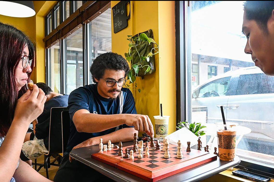 A group of young friends play chess while drinking boba tea at Central Tea House. Owner Phu Trinh keeps games to encourage customers to stay and have something fun to do while they eat banh mi and drink one of 144 different types of teas and smoothies they offer.