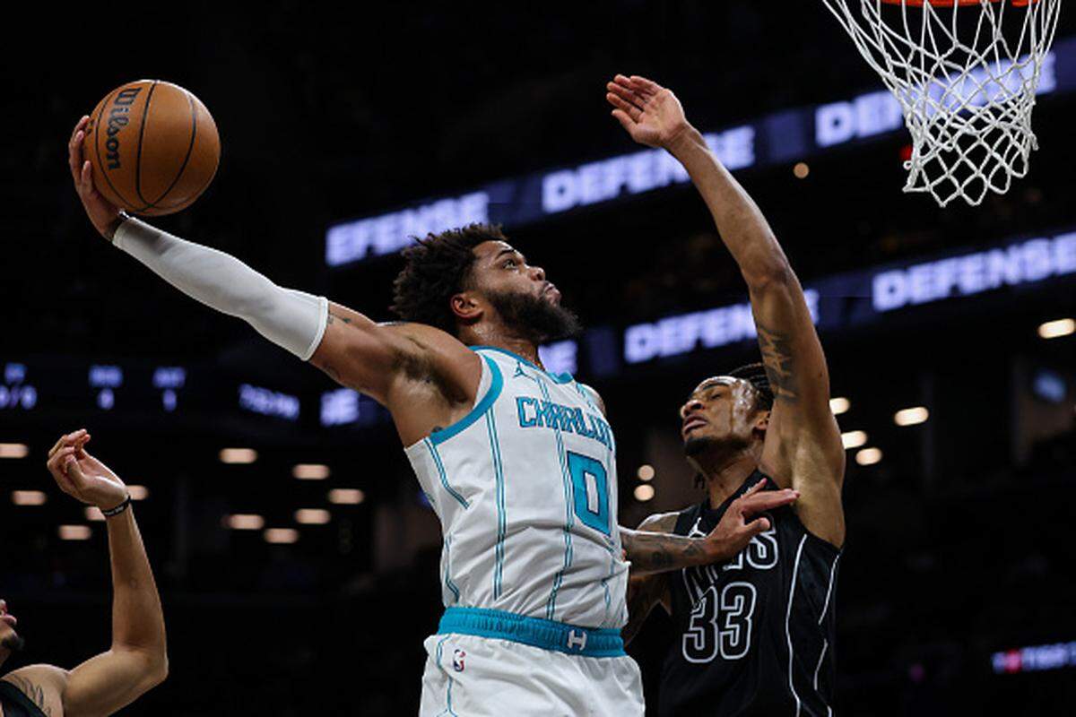 Miles Bridges of the Charlotte Hornets dunks the ball against Nic Claxton of the Brooklyn Nets.