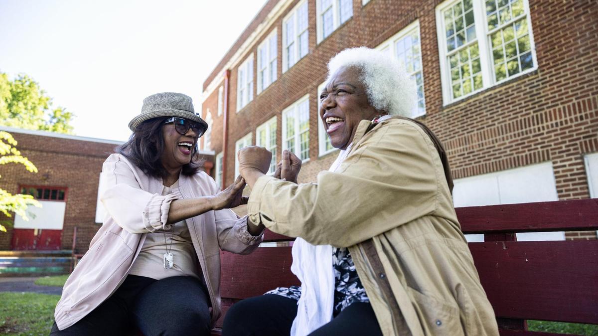 Berlinda Tolbert, left, and Mary Brown share a laugh as they reminisce on their childhood by playing “Patty Cake” and “Miss Mary Mack” outside of the former Morgan Elementary School in Charlotte, N.C., on Thursday, May 4, 2023. The two are longtime friends who met at the now closed Morgan School.