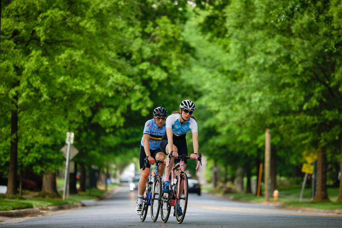 Cyclists ride along Selwyn Avenue under a canopy of trees along the “Booty Loop” bicycle course in Charlotte in April 2022.