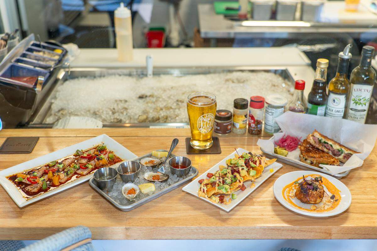 Hamachi crudo, St. Anne’s oysters, ahi tuna wontons, smoked prime rib panini, jumbo lump crab cake and a King Canary beer at Marlee Jean’s Raw Bar + Kitchen.