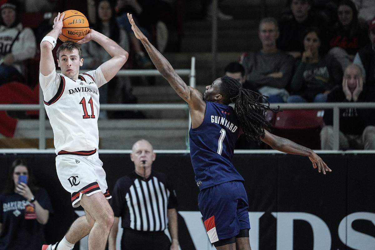 Davidson guard Sam Brown (11) looks to pass the ball away from Duquesne guard Tarence Guinyard (1) during the first half of an NCAA college basketball game, Tuesday, Dec. 30, 2025, in Davidson, N.C.