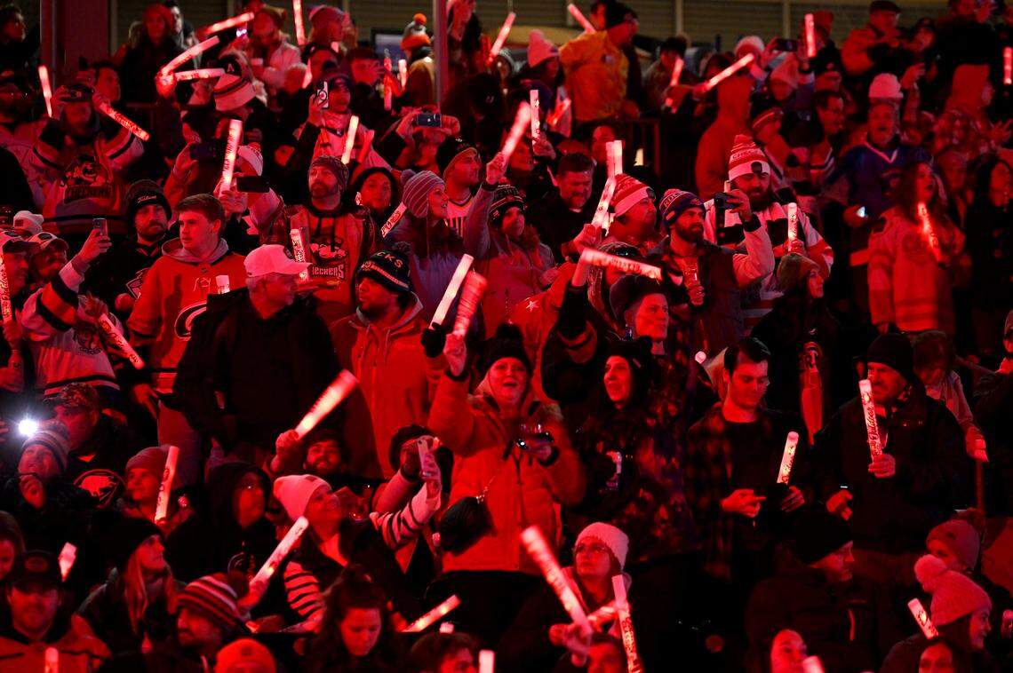 Fans are illuminated by red glow sticks as they prepare to watch the Charlotte Checkers battle the Rochester Americans during the 2024 Queen City Outdoor Classic at Truist Field in uptown Charlotte, NC on Saturday, January 13, 2024.