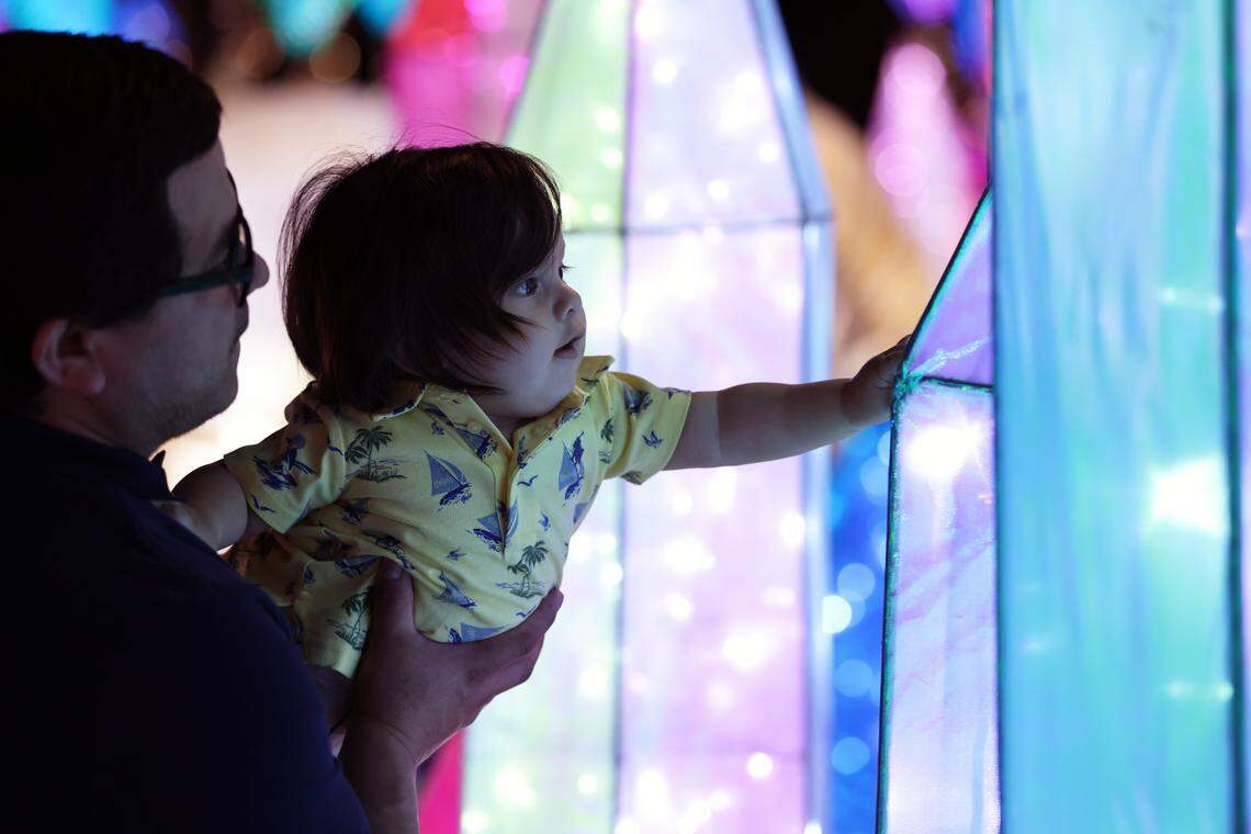 Jorge Gonzalez (left) and his one-year-old son Jorge Kilian (right) wander by shimmering ice formations at the Tianyu Lights Festival at Concord Mills, Charlotte, N.C., on Friday, April 25, 2025.