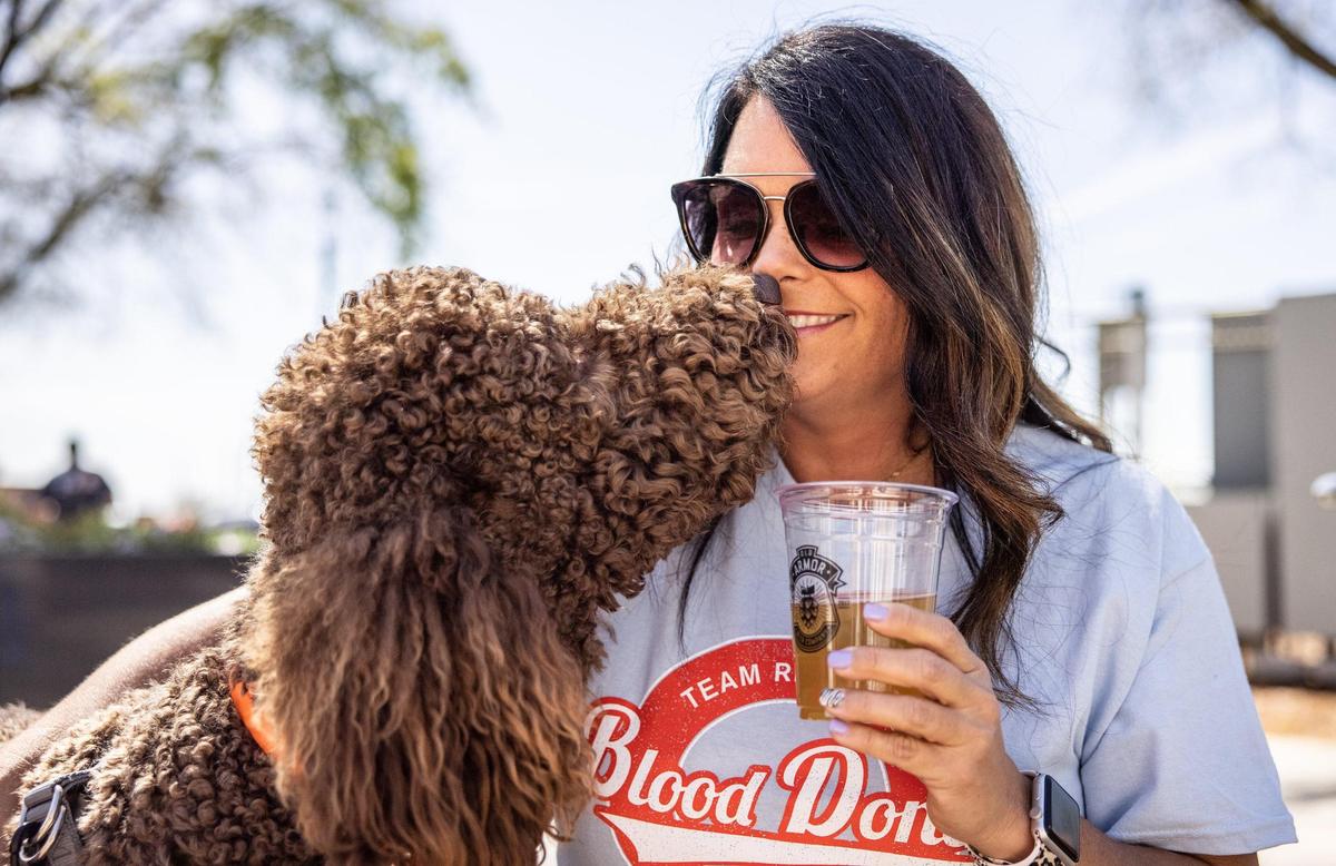 Mandy Overcash gets a kiss from her dog Kola while she drinks a beer April 15 in the social district in downtown Kannapolis.