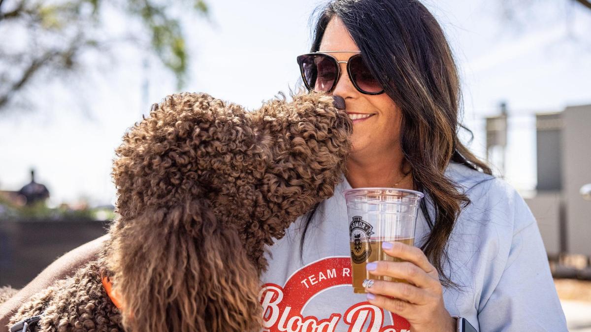 Mandy Overcash gets a kiss from her dog Kola while she drinks a beer April 15 in the social district in downtown Kannapolis.