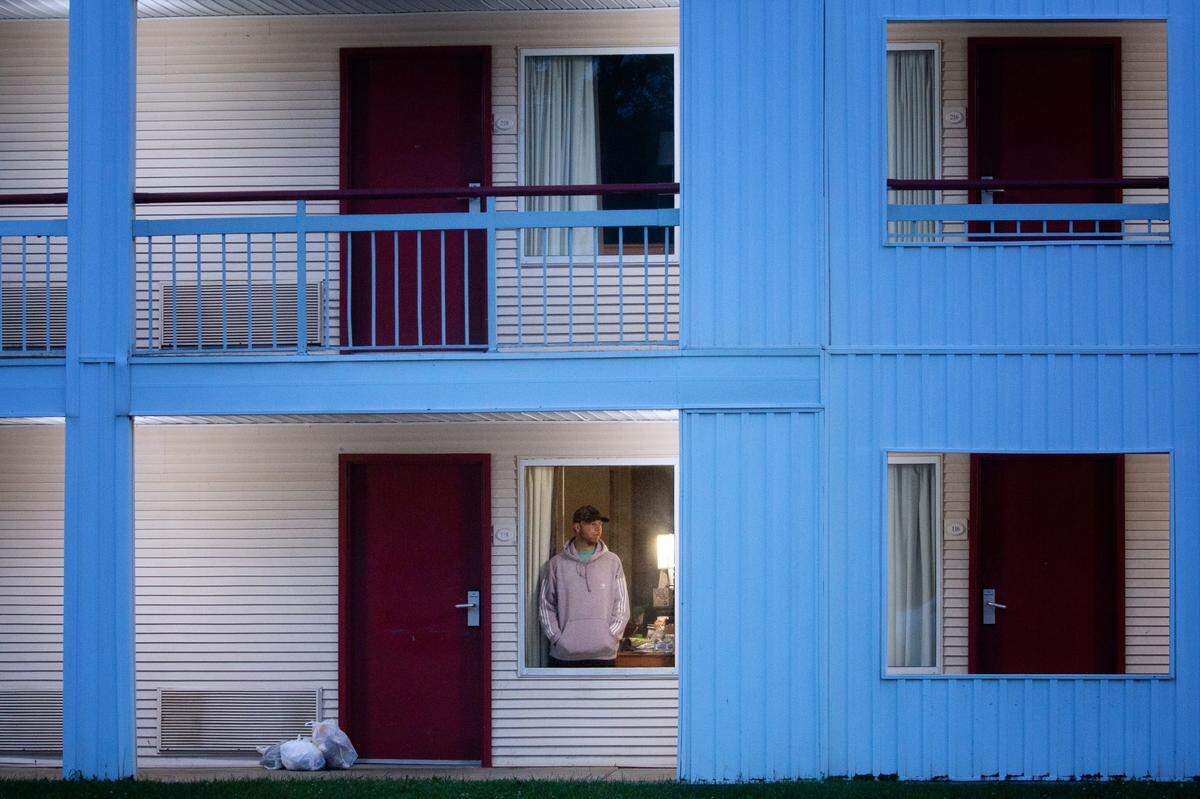 Aaron Hall, 32-year-old from Kansas City, seen through a window of the Econo Lodge near the Charlotte Douglas International Airport, where he stayed 10 days and nine nights in August after testing positive for COVID-19. Hall traveled to Charlotte from Chicago looking for a used Volvo 240 before getting sick from the coronavirus.