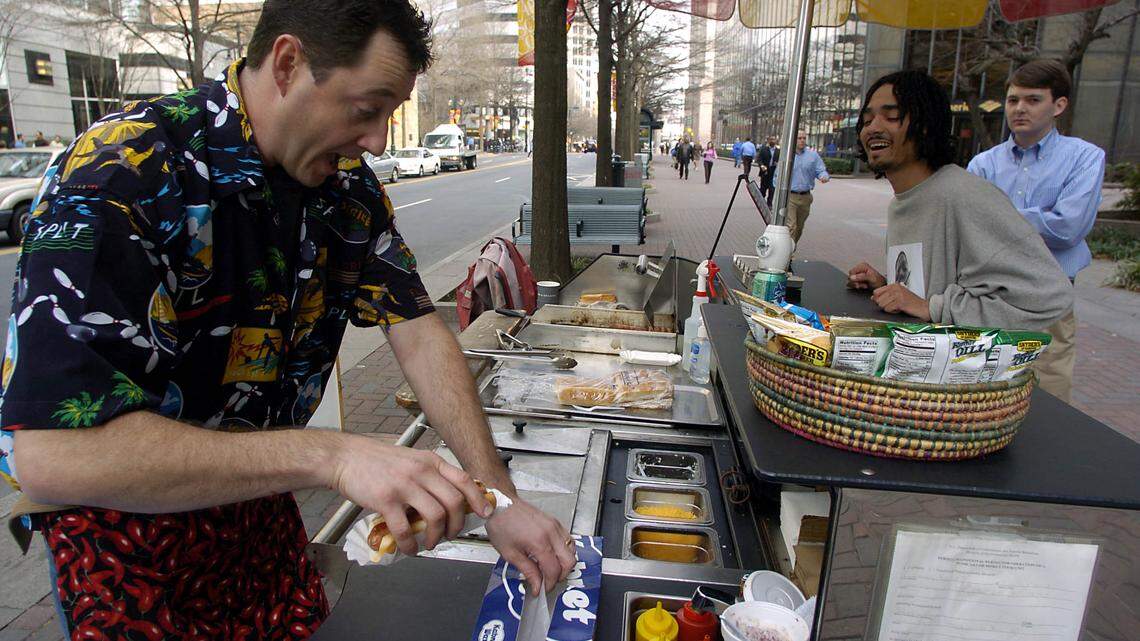 In this 2005 Charlotte Observer file photo, Victor Werany, "The Chili Man", jokes around while preparing a hot dog for Joe Miller, center,  as Clay McCullough waits his turn during lunch time.