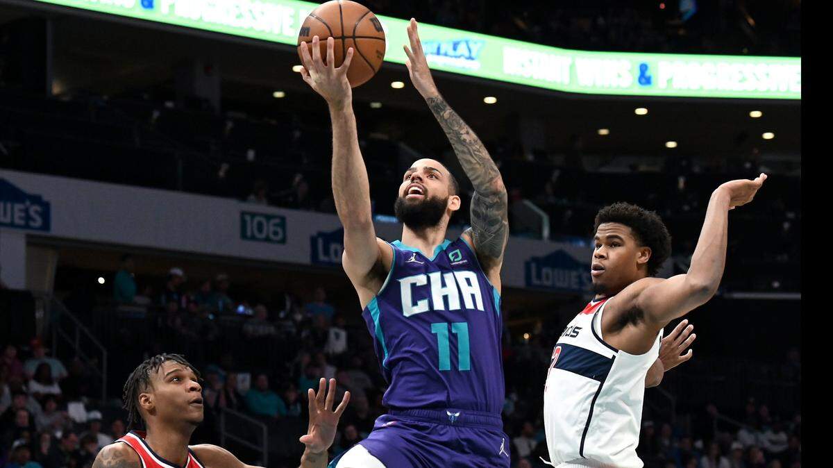 Charlotte Hornets forward Cody Martin, center, drives down the lane as Washington Wizards forward Isaiah Todd, left and center Vernon Carey Jr., right, look on during first half action at Spectrum Center in Charlotte, NC on Sunday, April 10, 2022.
