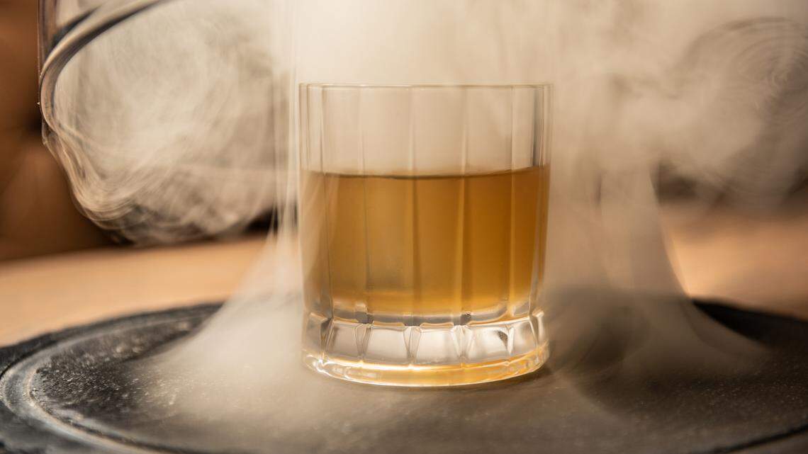 The Uncle Eddy is a cold smoked drink with pork belly fat-washed bourbon, apple oleo, tiki bitters and a king cube.