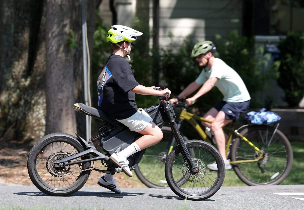 A youngster riding his e-bike down Westfield Road in Charlotte, NC passes a traditional bicycle on Tuesday, June 30, 2026.
