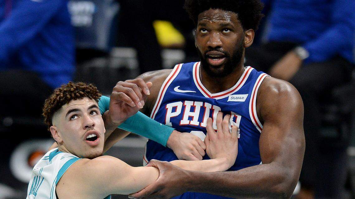 Philadelphia 76ers center Joel Embiid, right, wrestles in the lane with Charlotte Hornets rookie LaMelo Ball, left.