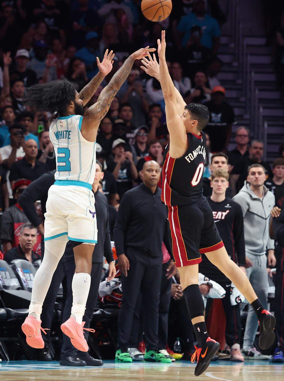 Charlotte Hornets guard Coby White, left, releases a three-point shot over Miami Heat forward Simone Fontecchio, right, on April 14. The Hornets defeated the Heat 127-126 in the NBA play-in-game.