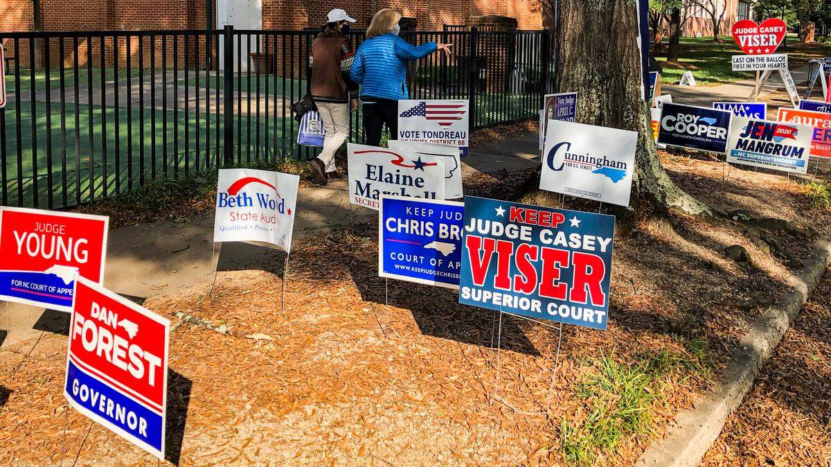 Campaign signs line Cherokee Road in Charlotte, NC as people mingle near precinct #18 on Tuesday, Nov. 3, 2020. Jeff Siner/The Charlotte Observer