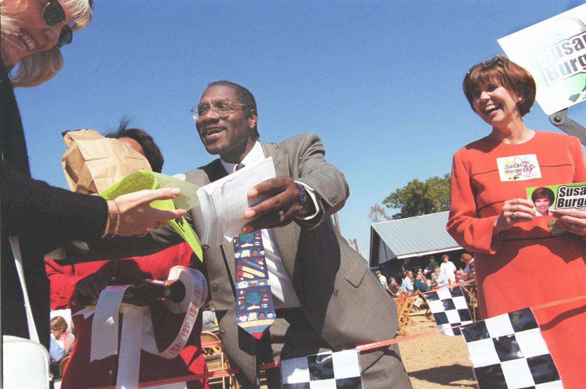 Arthur Griffin, running for school board and Susan Burgess, right, running for City Council at Large, meet Carol Livingston of Huntersville as she files past political candidates gathered at Thursday's Mallard Creek BBQ Oct. 28, 1999