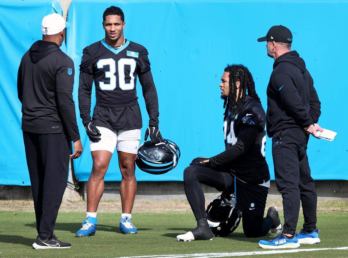 Carolina Panthers rookie running back Jonathon Brooks, second from right, takes a knee as running back Chuba Hubbard, second from left, speaks with team personnel during practice on Monday, November 18, 2024.
