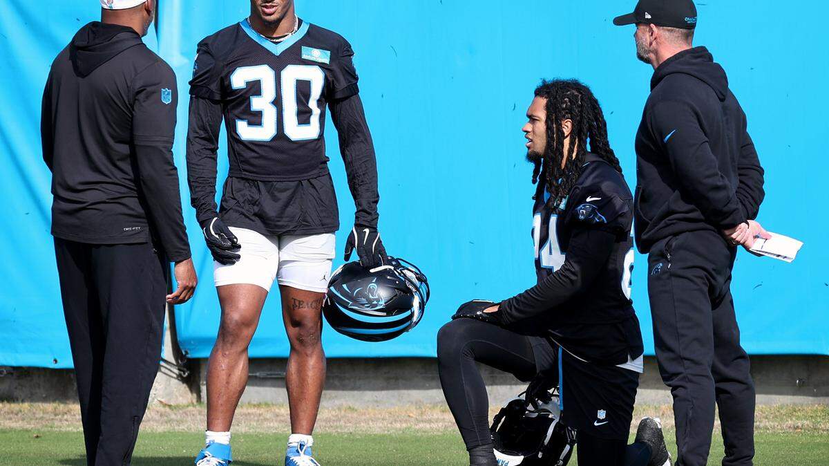 Carolina Panthers rookie running back Jonathon Brooks, second from right, takes a knee as running back Chuba Hubbard, second from left, speaks with team personnel during practice on Monday, November 18, 2024.